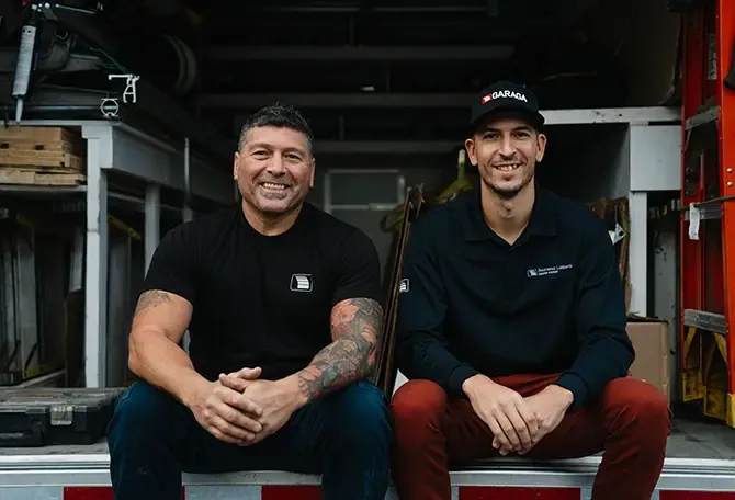 Installateurs souriants de porte de garage assis dans leur camion